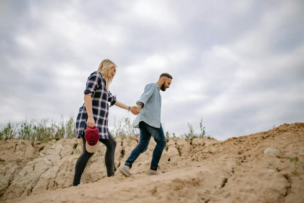 Man Leading Woman by Hand Across Sand Dunes