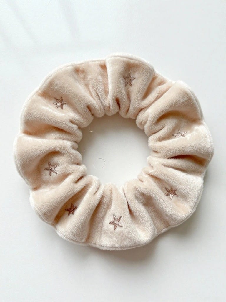 Beige scrunchie with small embroidered stars scattered around the band.