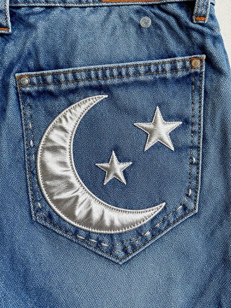 Jeans back pocket embroidered with silver crescent moon and two stars.