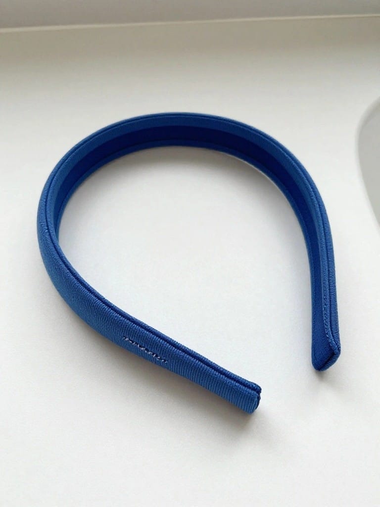 A wide curved blue fabric headband rests on a white sink counter.
