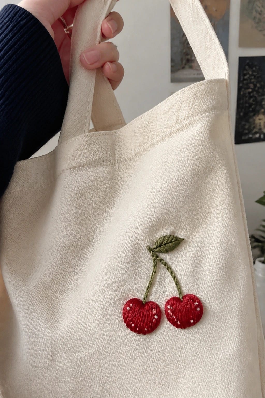 A cream tote bag with two red embroidered cherries and green stems on the lower front.