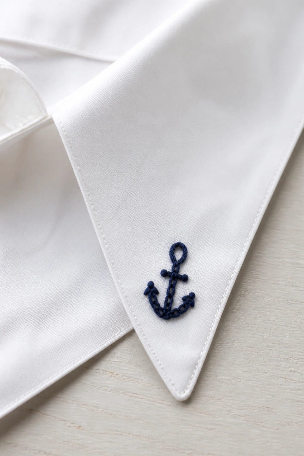 White shirt collar with three small daisies embroidered in white, yellow, and green thread.