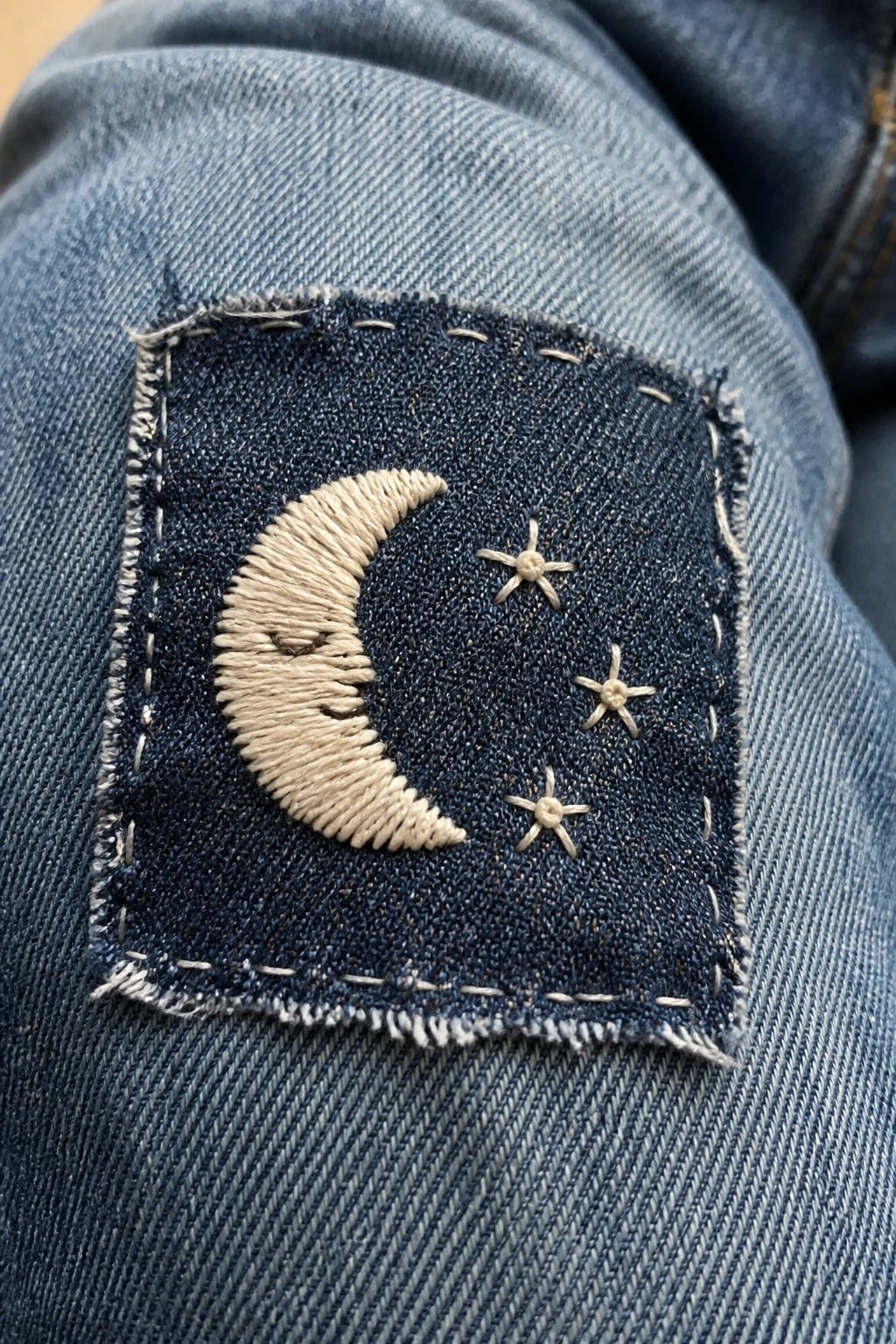Denim patch with sleeping crescent moon and three stars on blue jeans