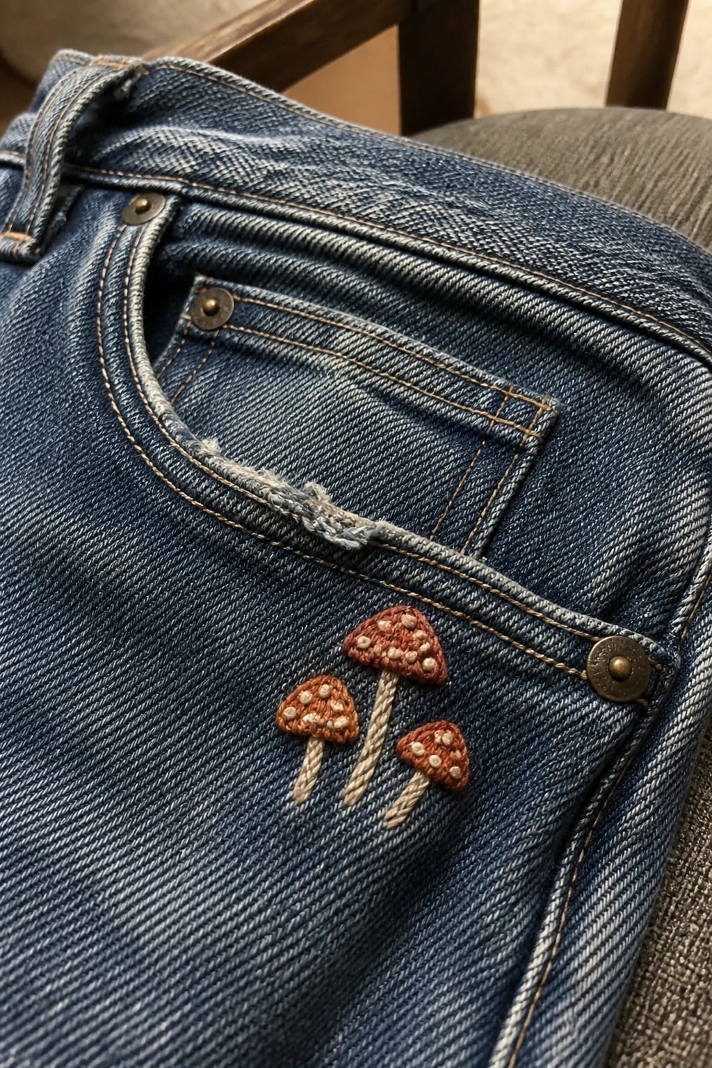 A small blue embroidered sailboat sits on the back pocket of blue denim jeans.