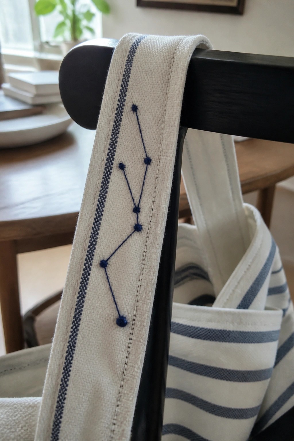 White canvas strap with blue diamond embroidery draped over black wooden chair