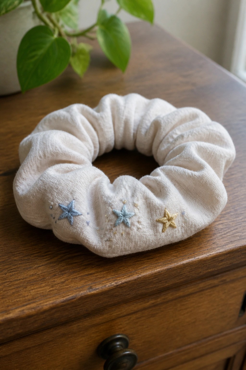 White scrunchie with embroidered blue and gold stars on wooden table