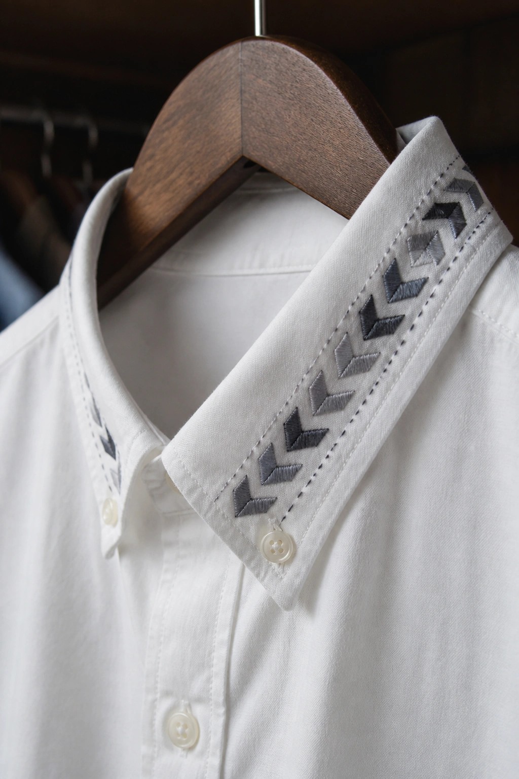 White button-up shirt collar with dark chevron embroidery along the edge.