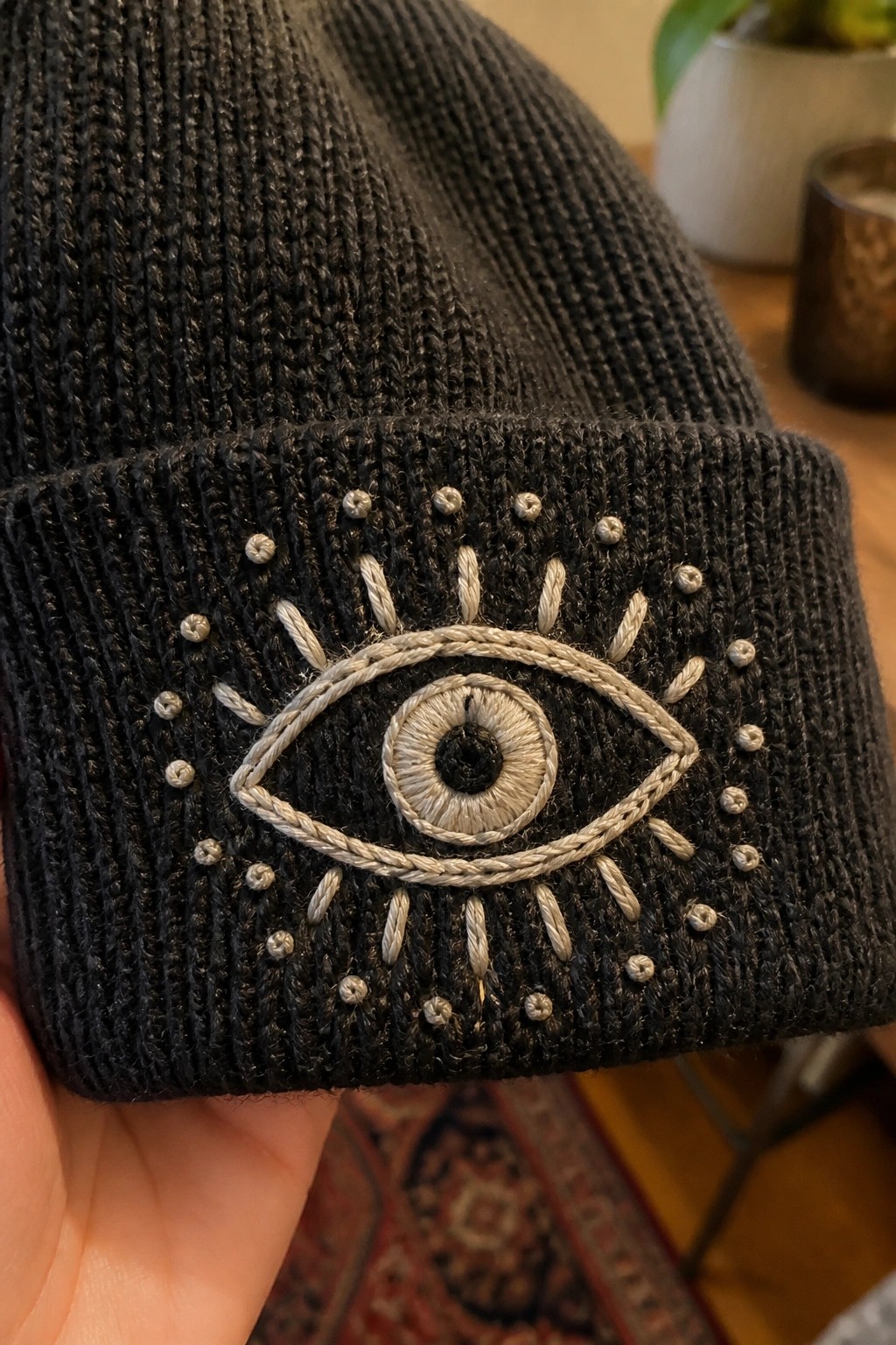 Black knit beanie cuff with embroidered eye and surrounding silver bead accents
