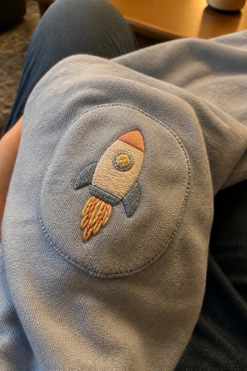 Embroidered rocket with orange tip and flames on light blue pants knee