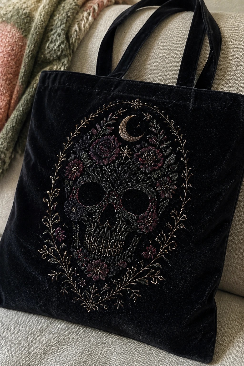 Black velvet tote bag with a central embroidered floral skull, crescent moon, and circular vine wreath.