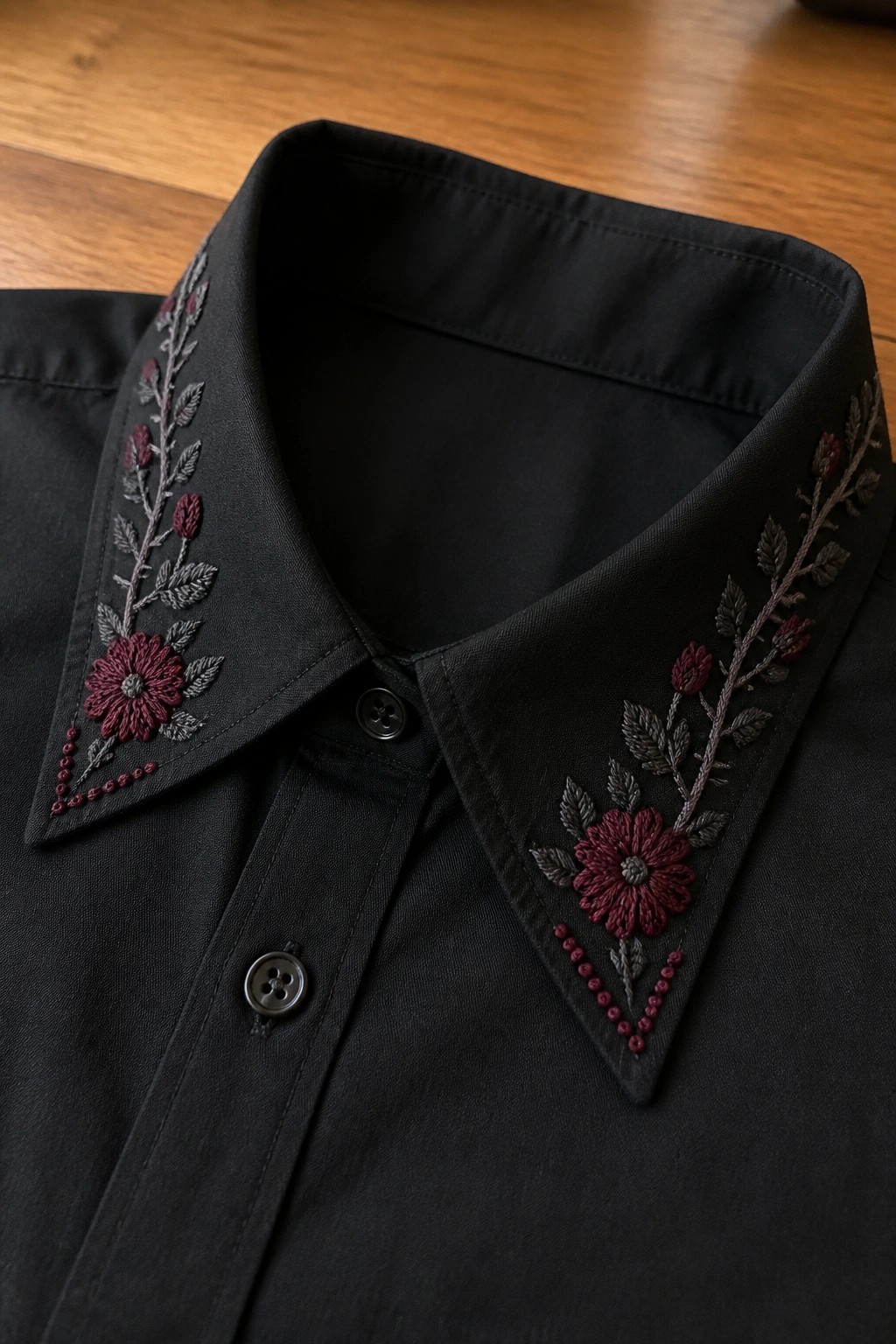 Close-up of black shirt collar with maroon flowers and gray leaves embroidered on both points.