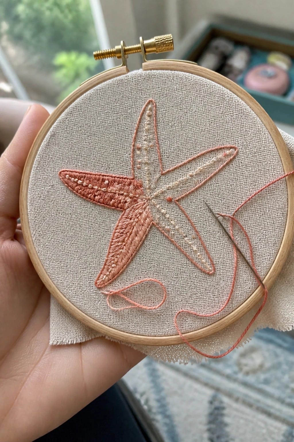 Hands stitching floral embroidery of daisies in wooden hoop on table
