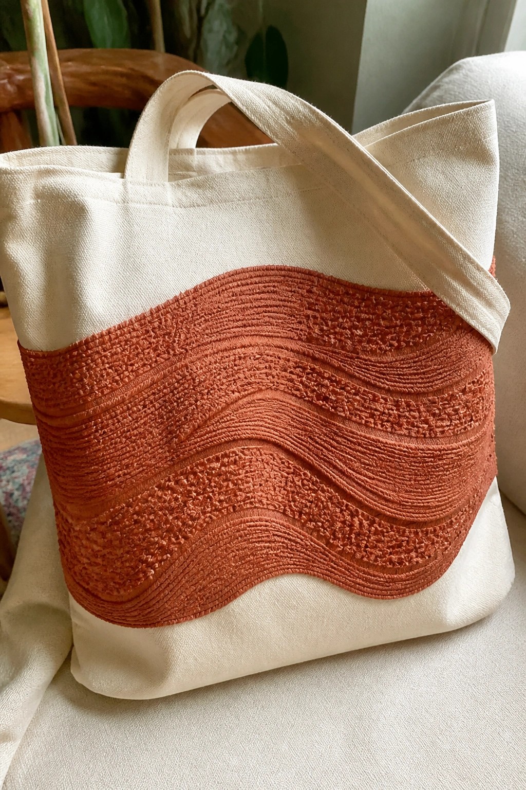 Cream canvas tote bag with wavy orange ruched texture and handles.