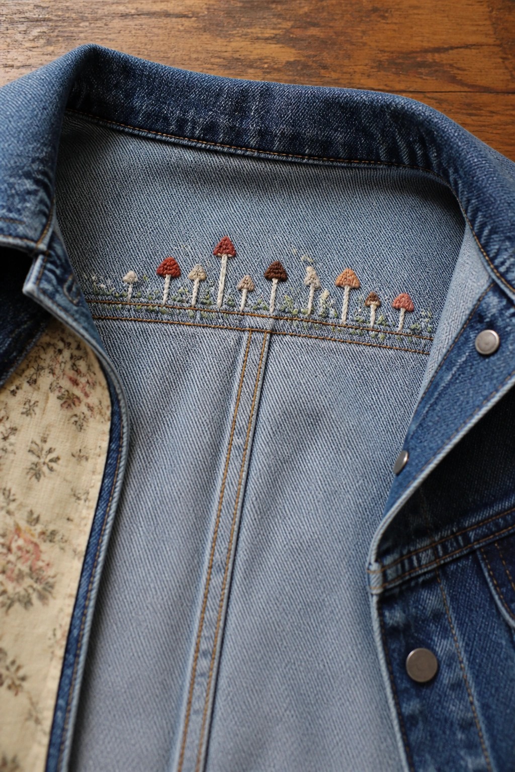 Blue denim jacket collar embroidered with a row of colorful mushrooms.