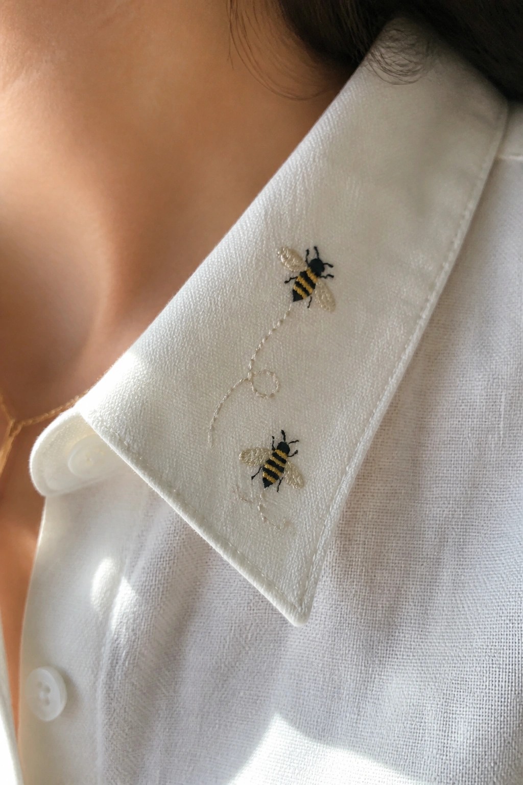 Embroidered bumblebee on green leaf with white flowers on linen cloth