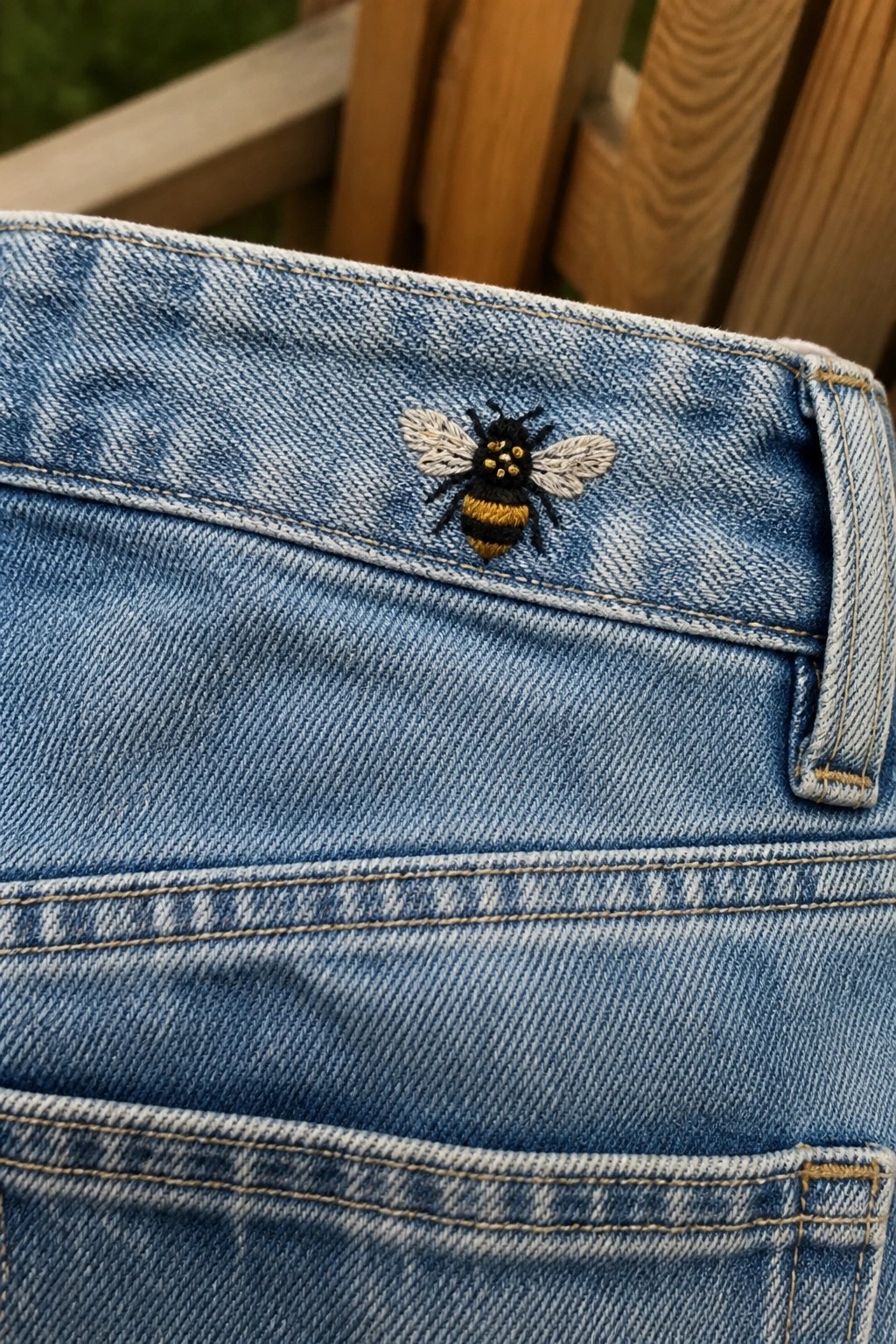 Blue denim jeans with embroidered black and yellow bee on waistband