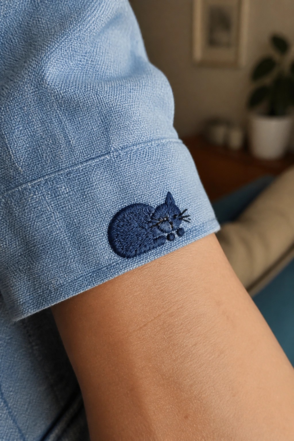 Rolled light blue denim cuff with dark blue embroidered sleeping cat.