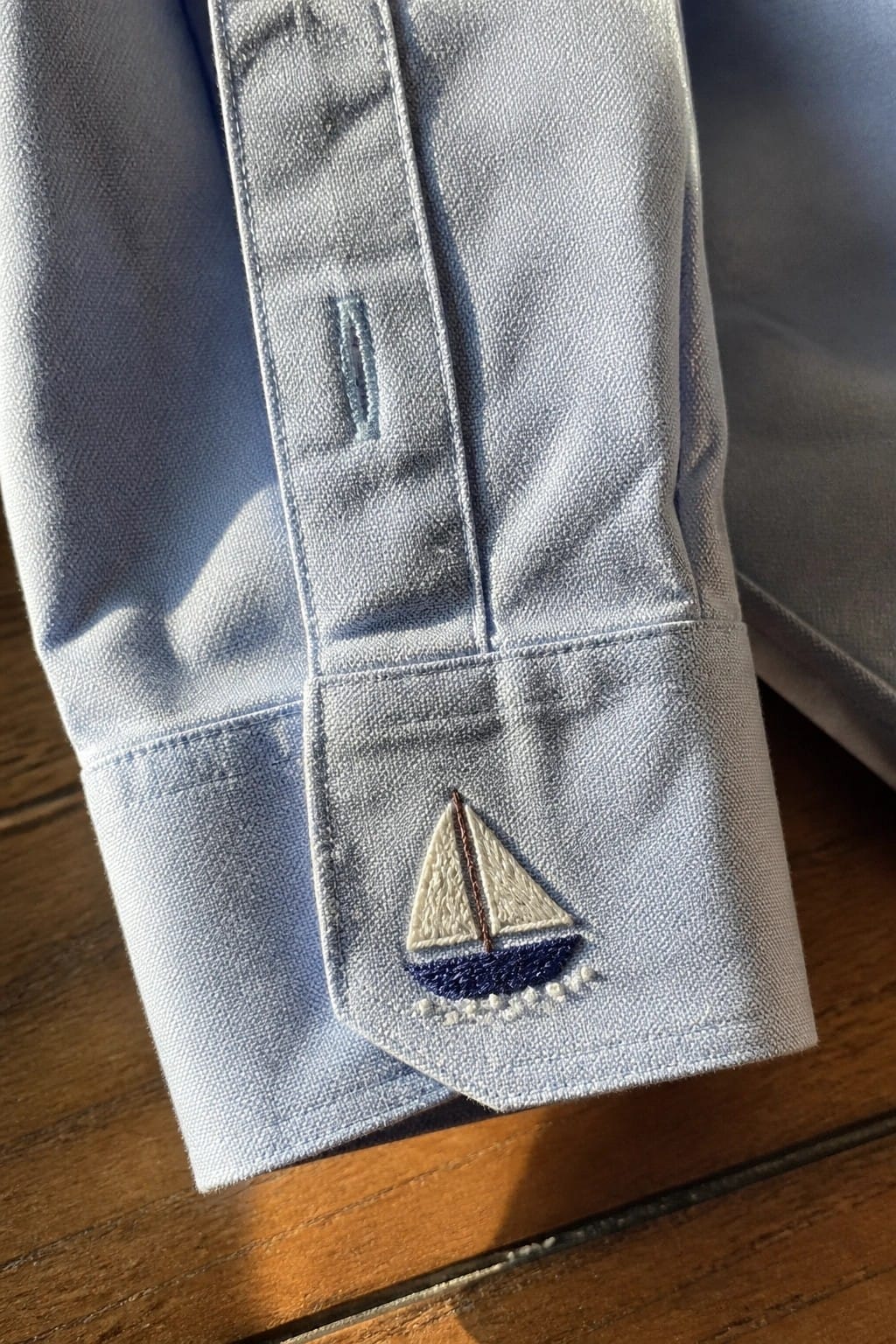Close-up of a cream shirt collar with green embroidered vines and leaves running along both edges.