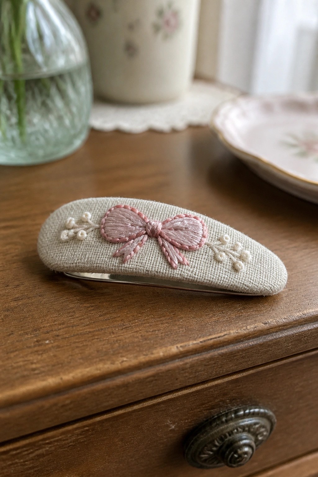 Embroidered bookmark with two birds on leafy branches beside a book and lamp
