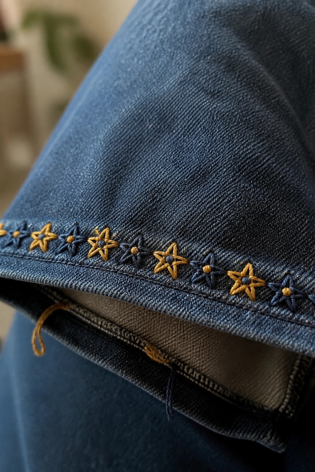 Blue denim fabric with alternating yellow and navy star embroidery along seam