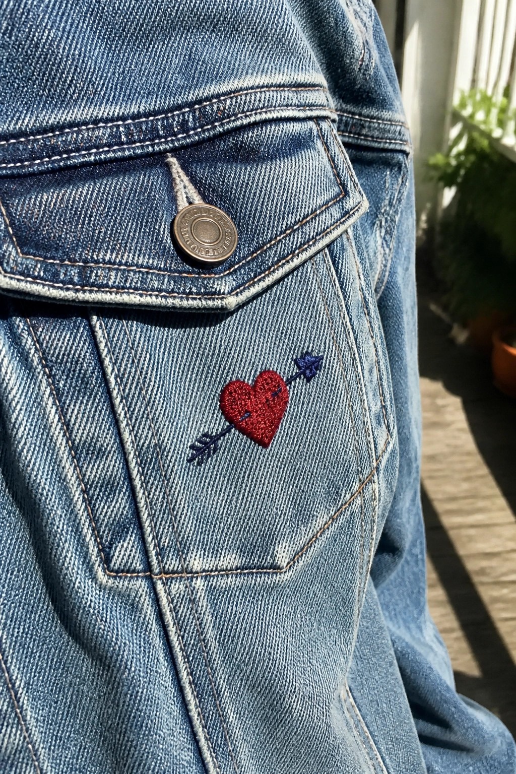 Blue denim jacket pocket with red heart and blue arrow embroidery
