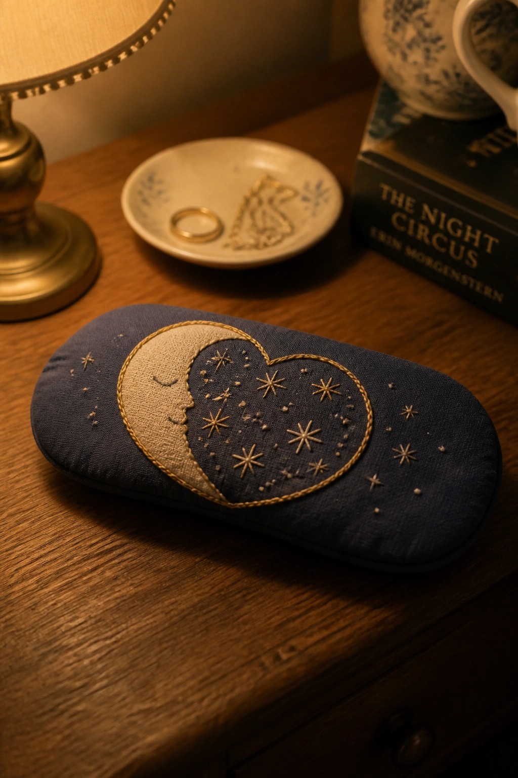 Navy blue embroidered pouch with golden moon, heart, and stars on wooden table