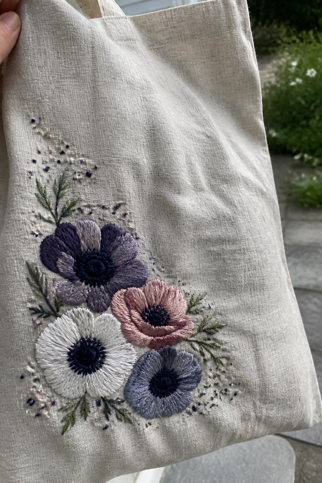 Beige canvas tote bag with embroidered purple, pink, white, and blue flowers.