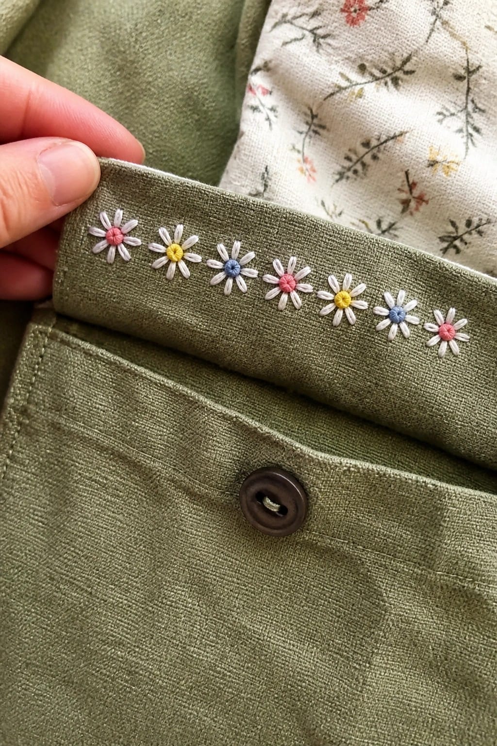 Denim jacket cuff with embroidered gray anchor and blue wavy stitches