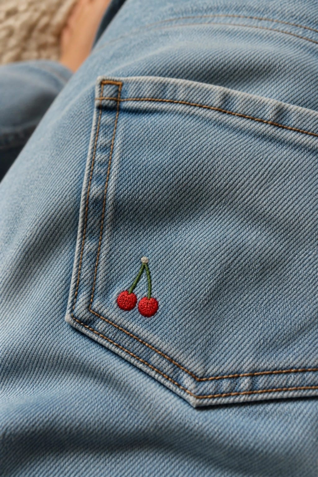 Blue jeans with constellation embroidery in a hoop on wooden table with supplies