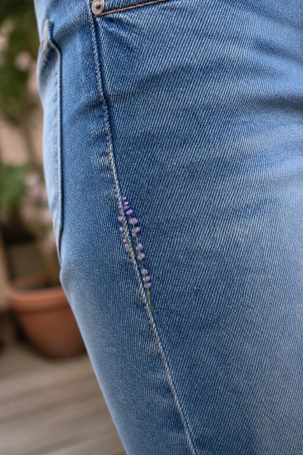 Light blue denim jeans cuff with purple embroidered lavender on wood