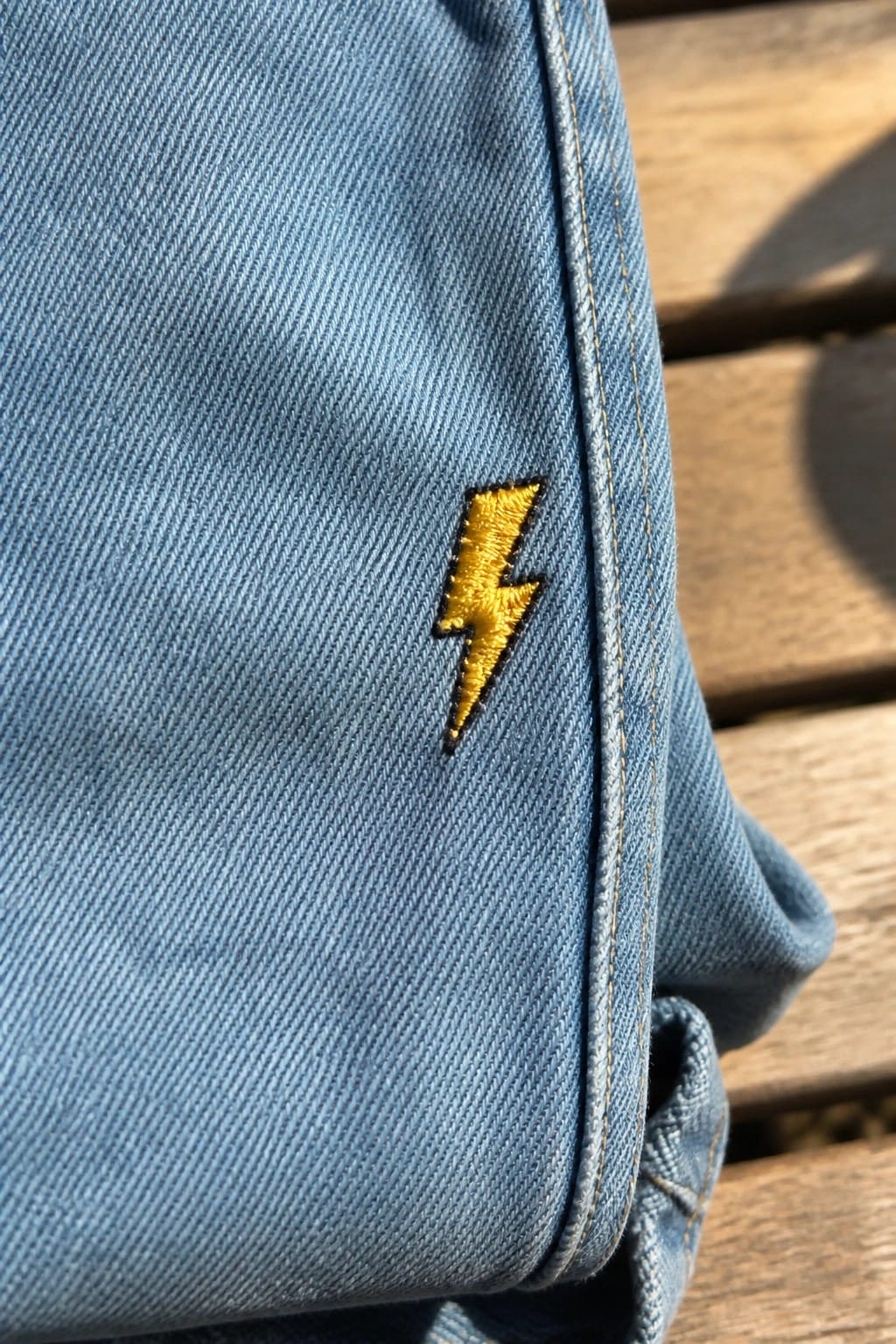 White moon phase embroidery stitched across the waistband of blue denim jeans.