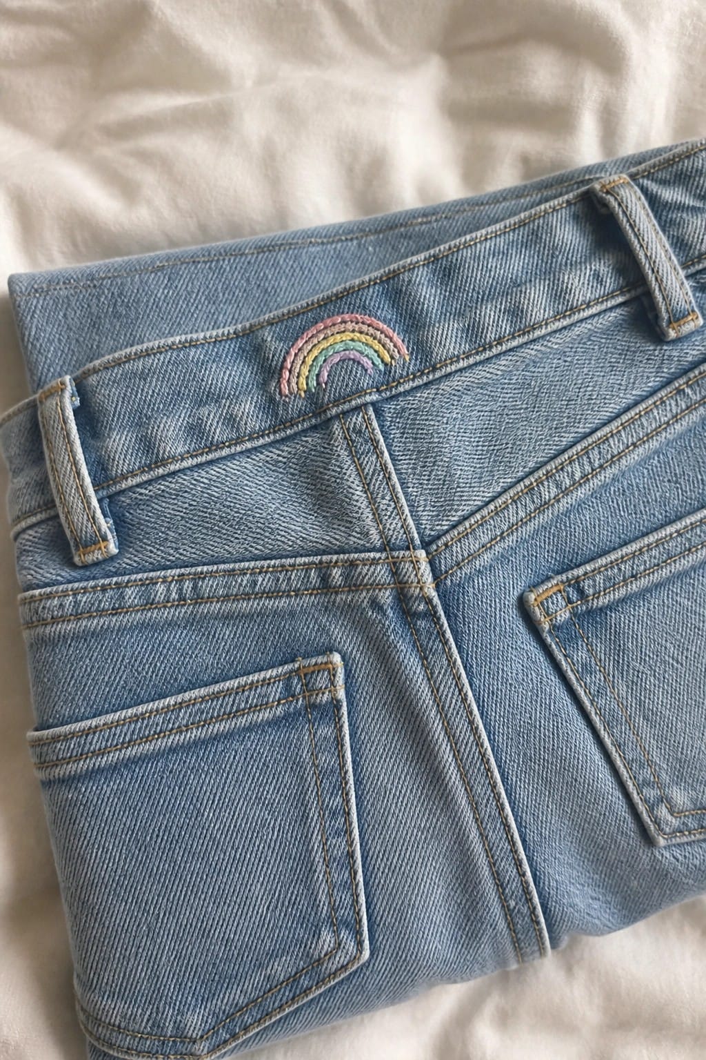Two small white daisies with yellow centers embroidered on the white fabric inside a blue denim pocket.