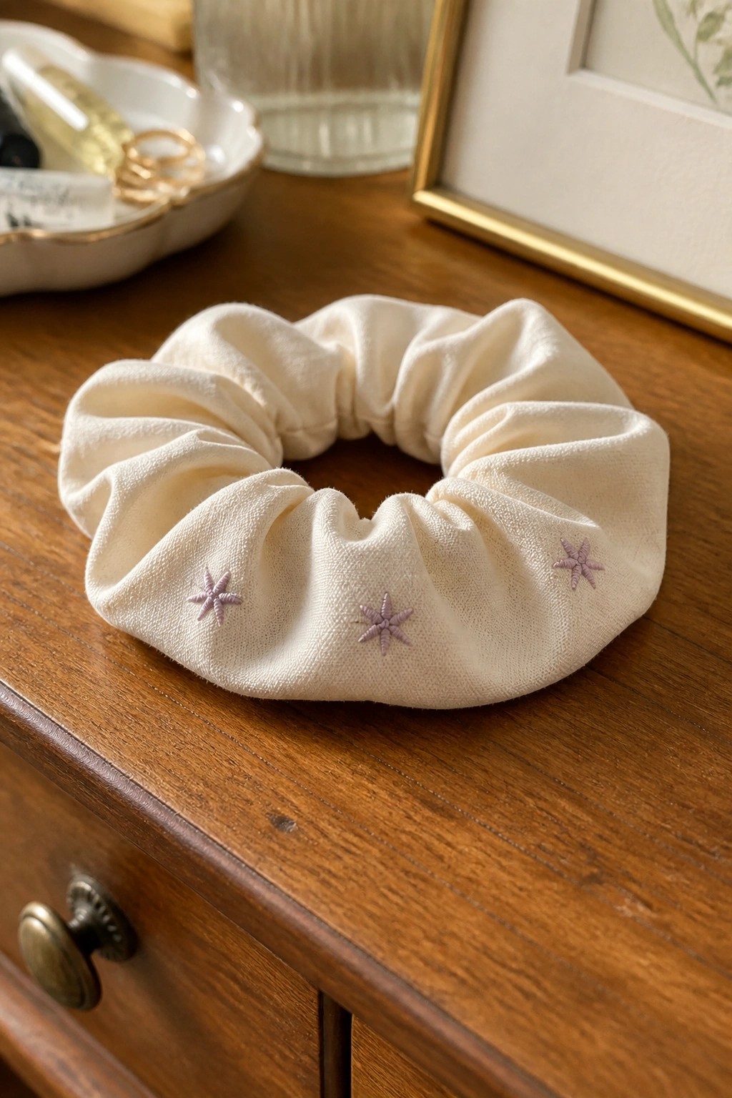 Off-white scrunchie with purple star embroidery on wooden dresser surface