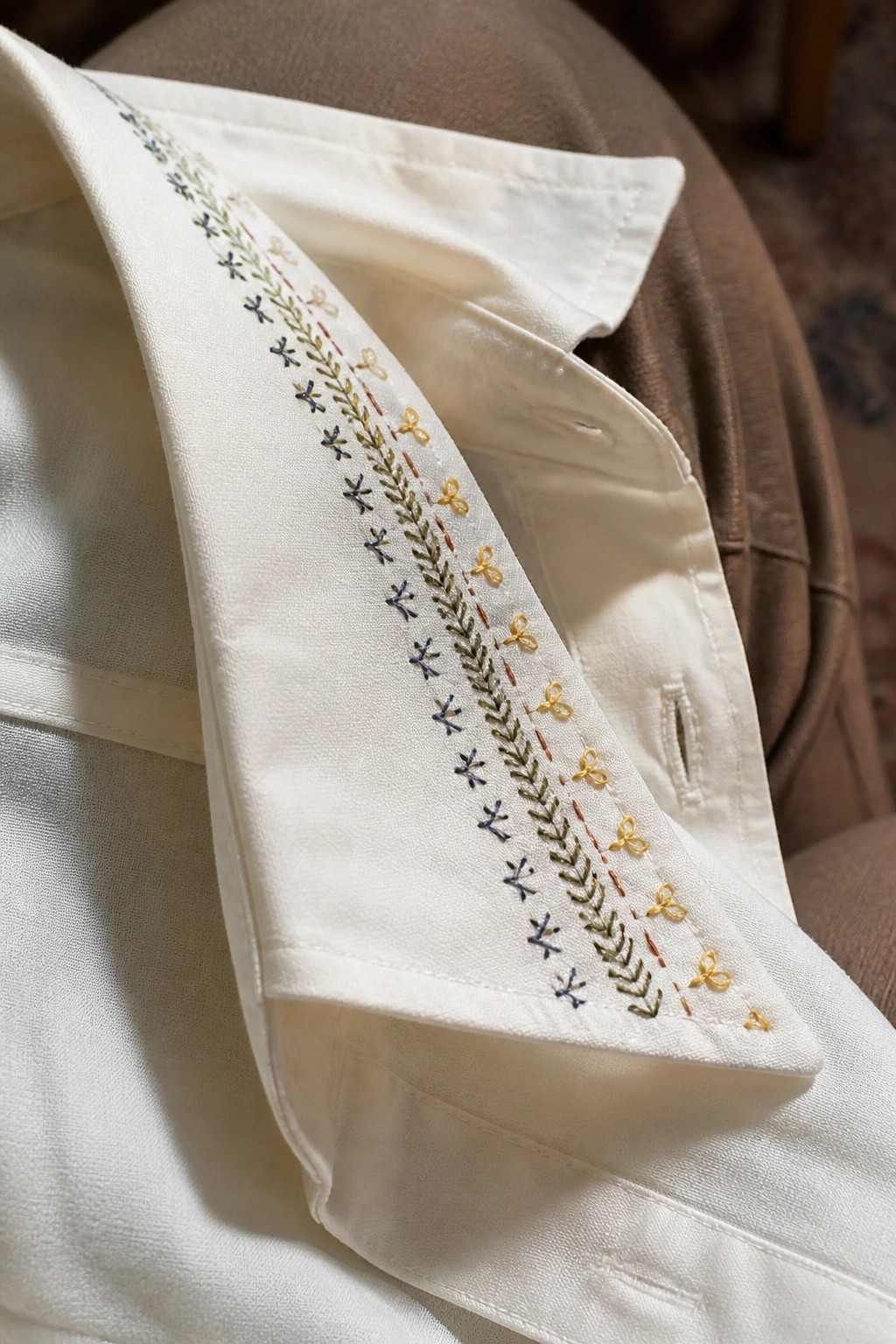 White shirt collar embroidered with blue X's, green leaves, and yellow bows.