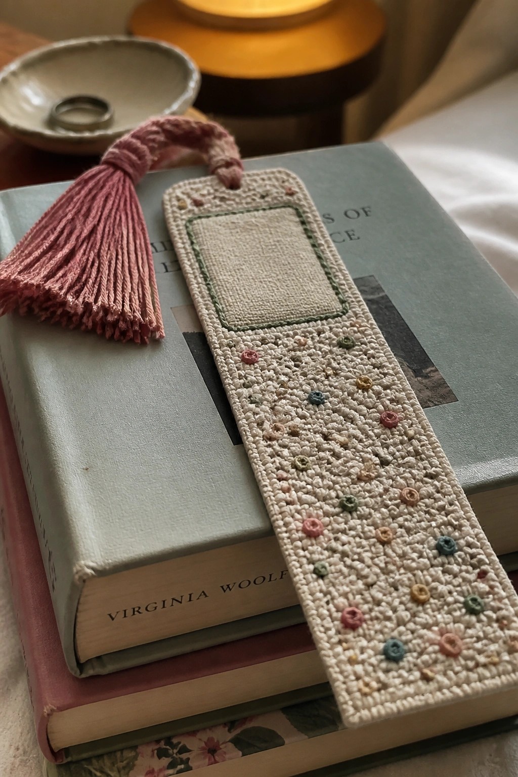 Embroidered floral bookmark with pink tassel on stacked Virginia Woolf books
