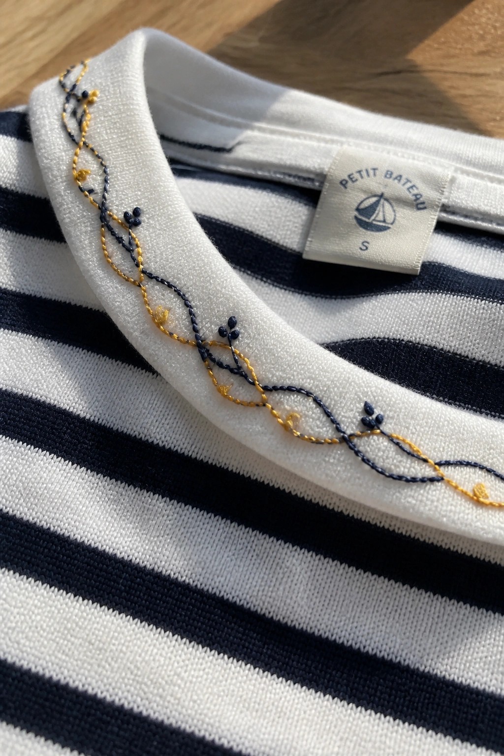Navy and white striped t-shirt with yellow-blue embroidered collar and Petit Bateau tag.