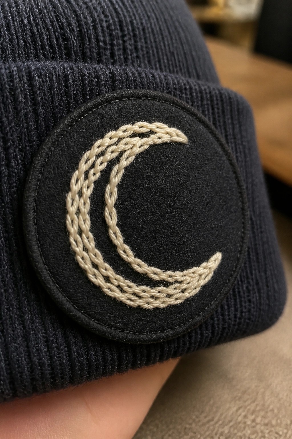 Navy blue knitted beanie with black patch and cream crescent moon embroidery