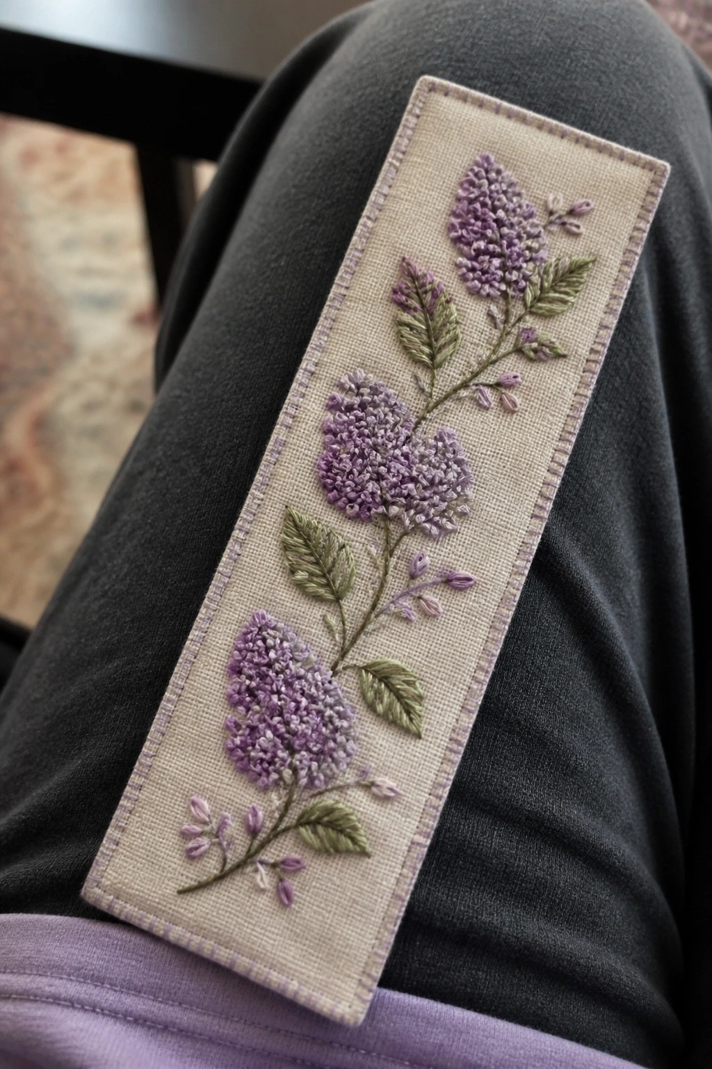 Beige fabric with purple lilac embroidery and green leaves on gray pants