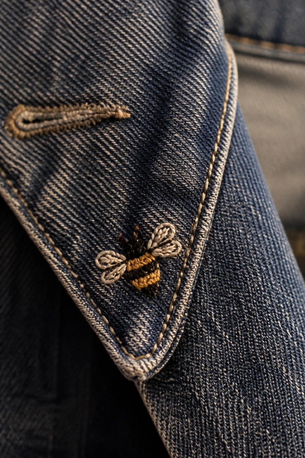 Blue denim fabric with embroidered bumblebee and small curved design