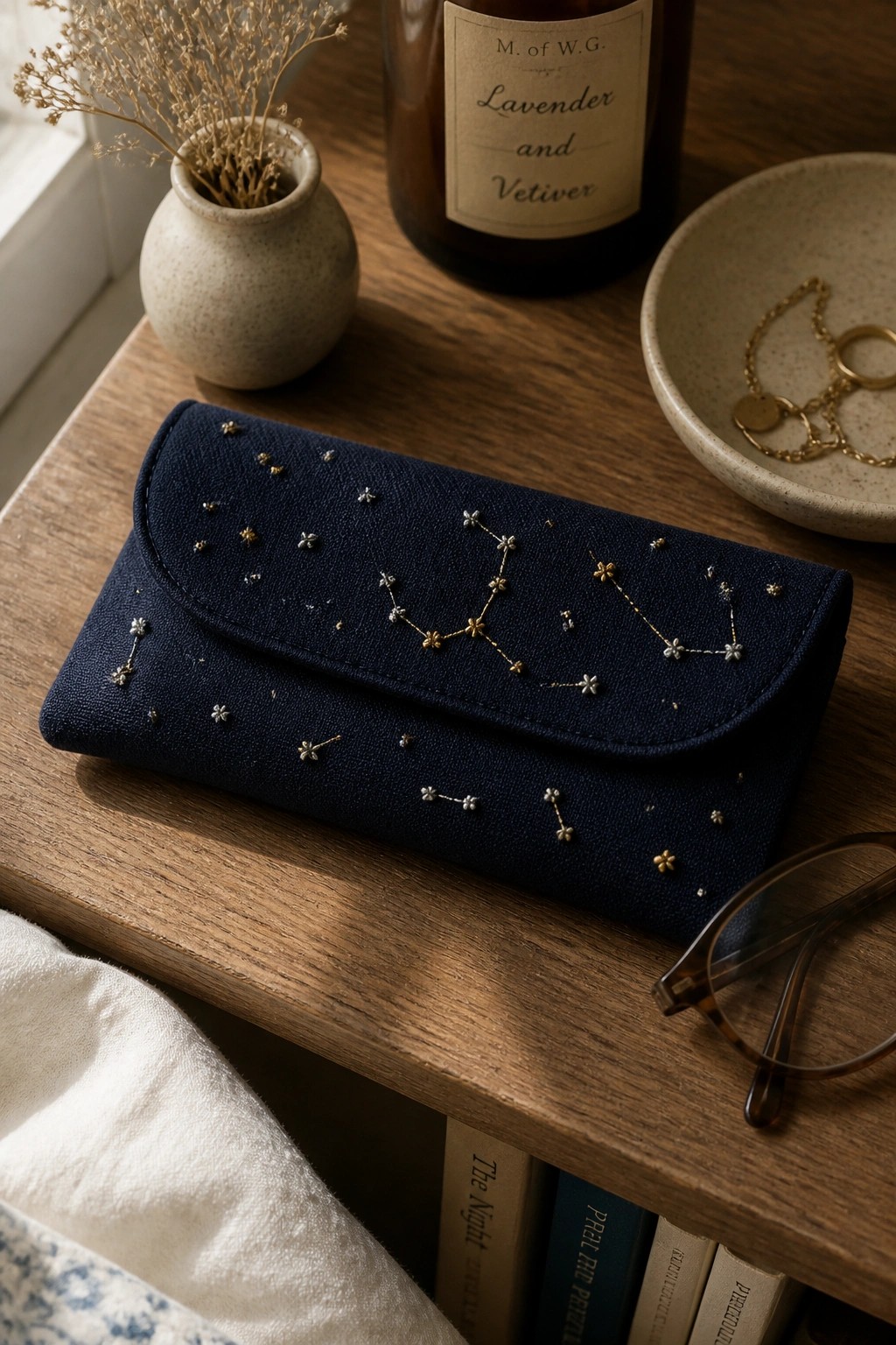 Navy blue clutch embroidered with gold constellation stars on wooden table beside glasses