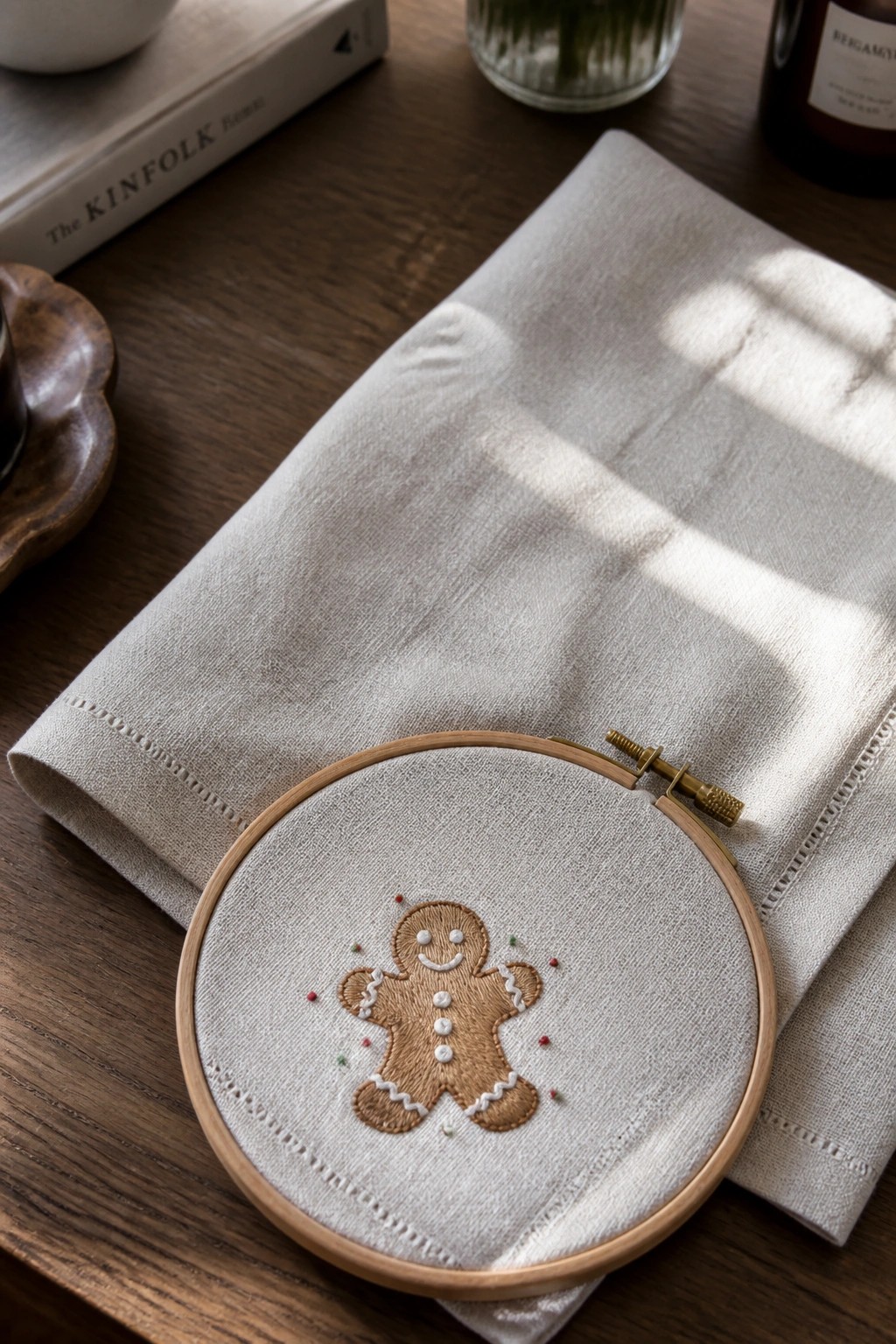 Embroidered gingerbread man in wooden hoop on beige fabric over wooden table