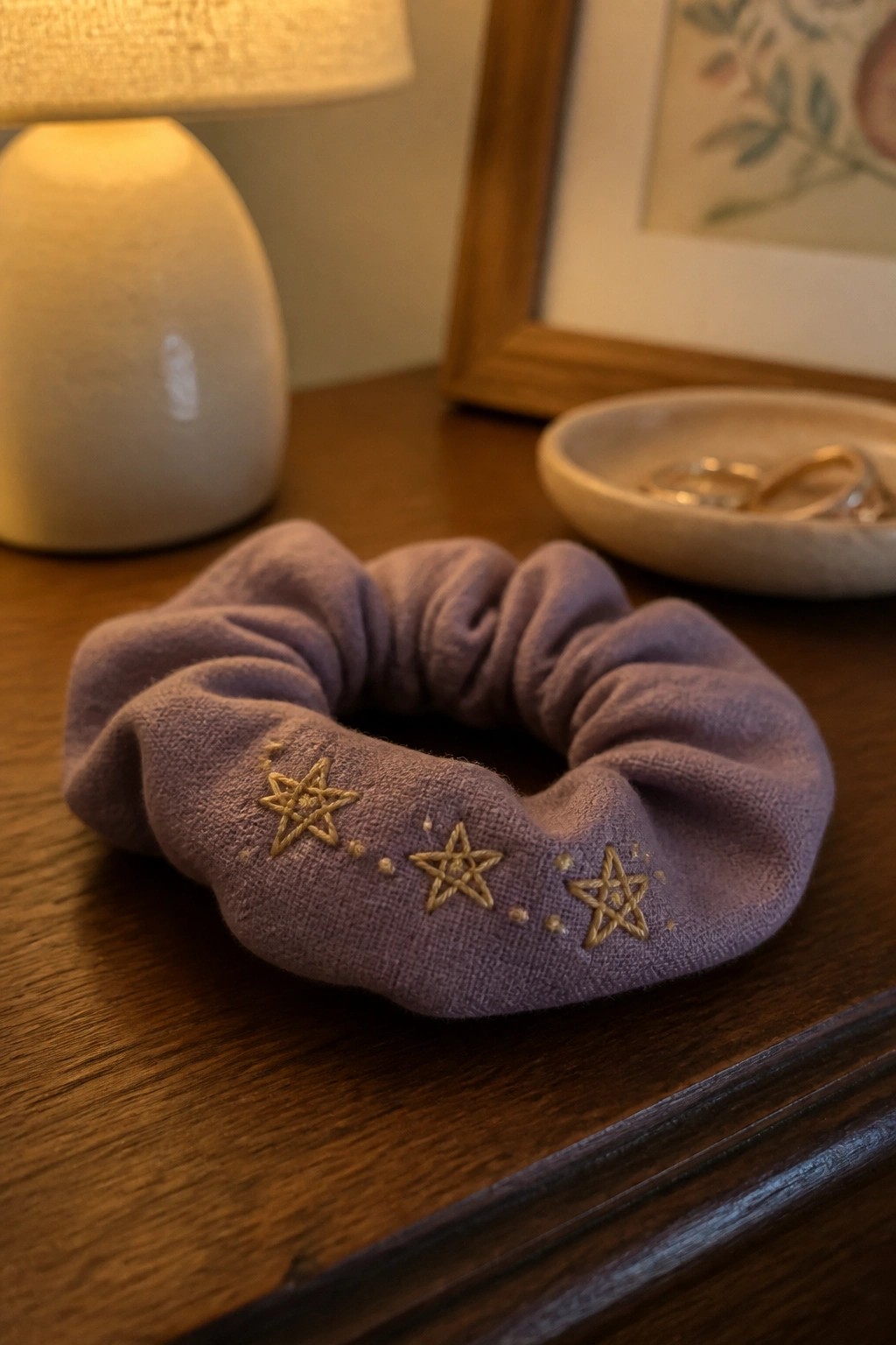 Velvet purple scrunchie with gold star embroidery on wooden table near lamp
