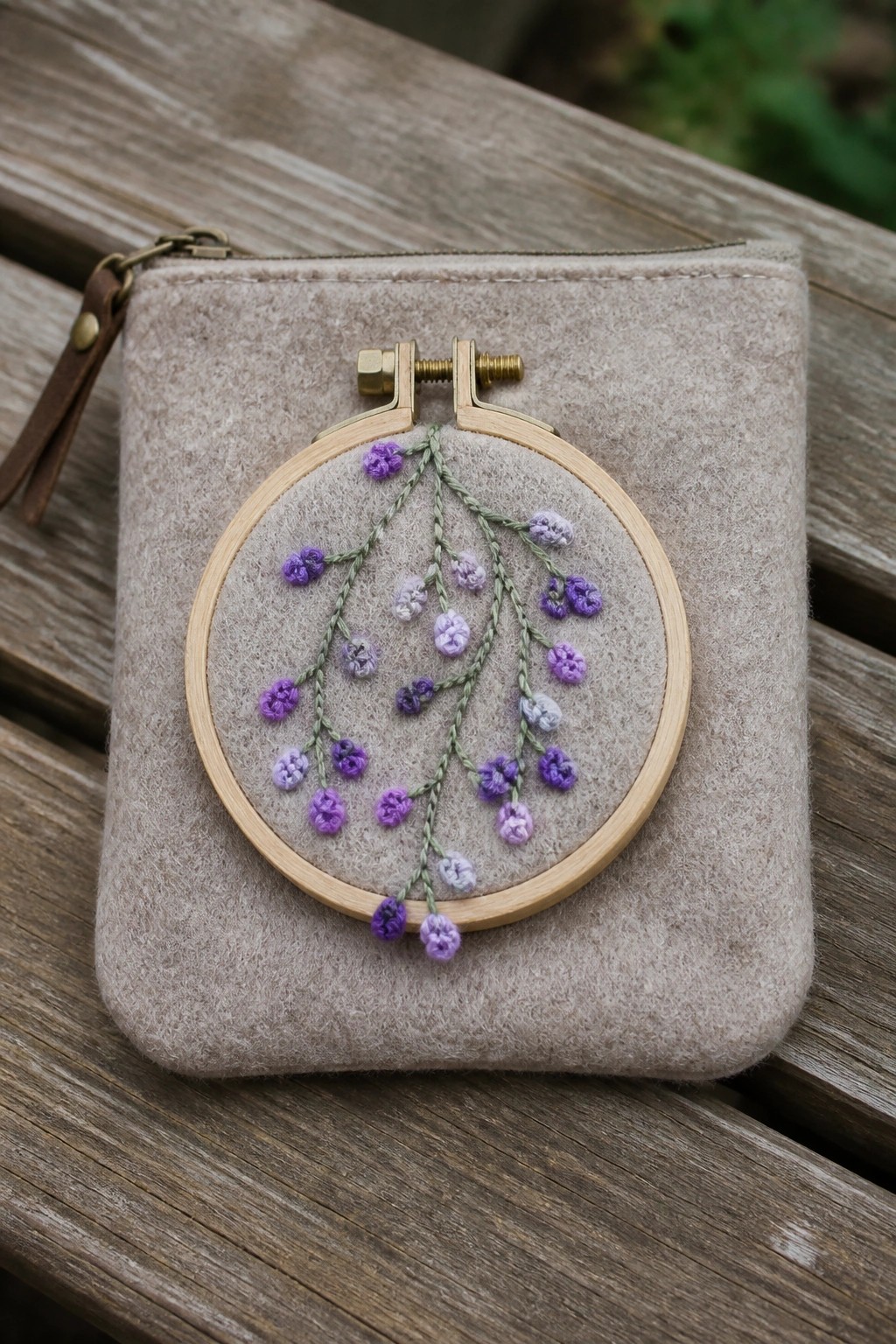Wooden hoop with purple embroidered flowers on beige felt zip pouch