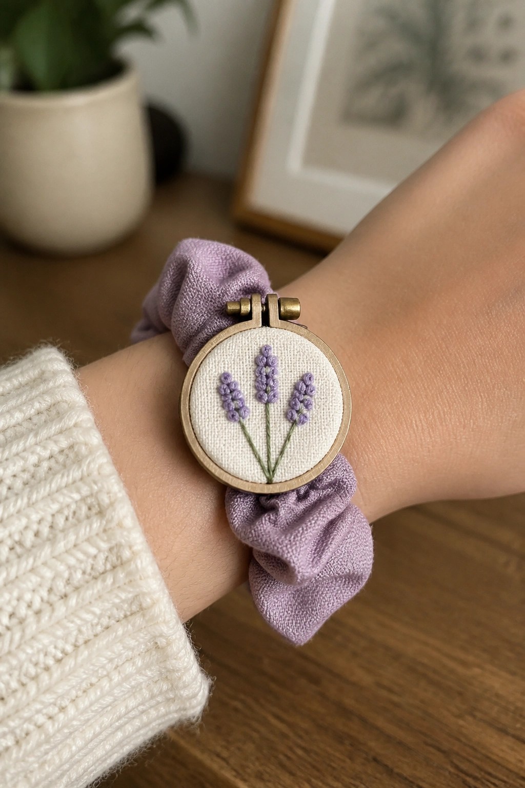 Wrist in white sweater wearing lavender scrunchie with embroidered lavender hoop
