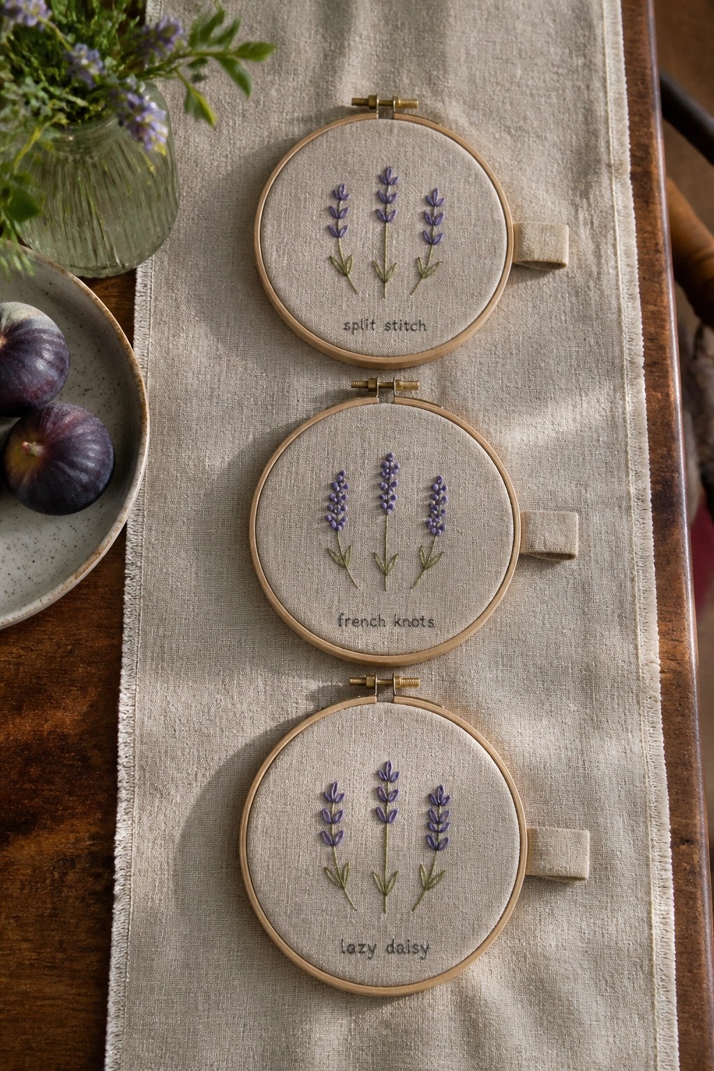 Three embroidery hoops with lavender designs labeled split stitch, french knots, lazy daisy.
