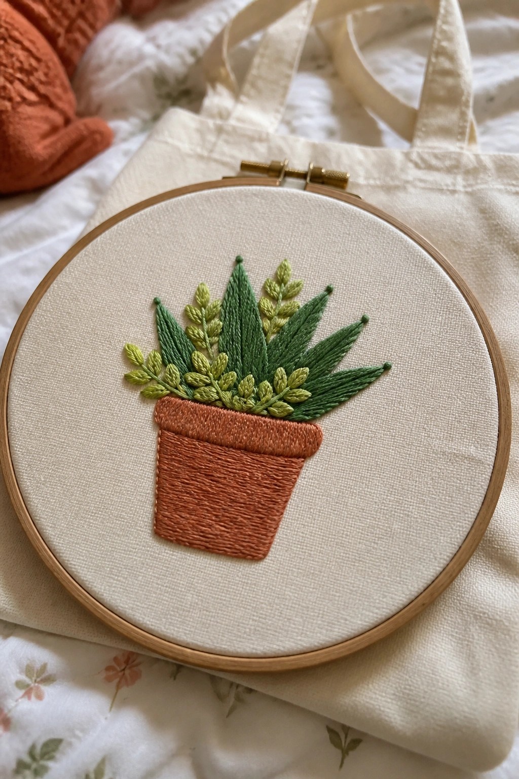 Wooden embroidery hoop with stitched potted plant on canvas tote bag