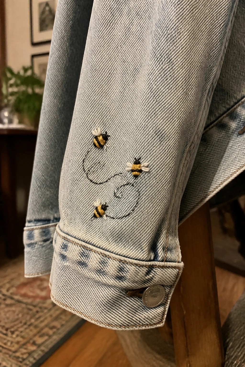 Light blue denim jacket sleeve with three embroidered bumblebees and dashed lines.