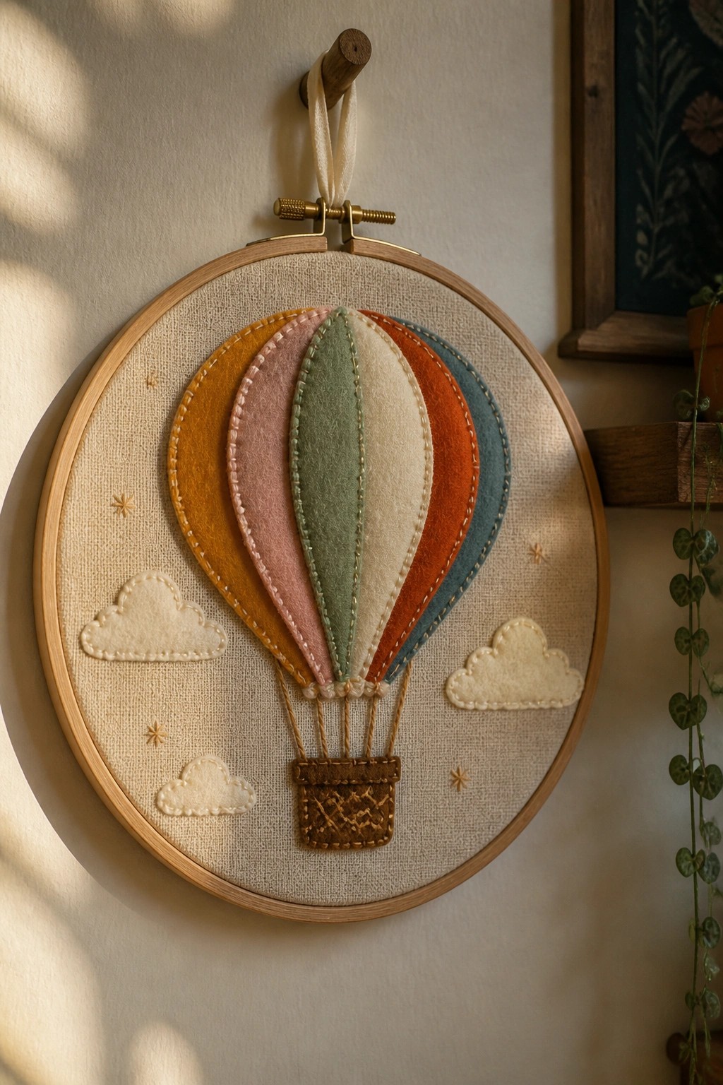 Colorful felt hot air balloon embroidery in wooden hoop with clouds and stars.