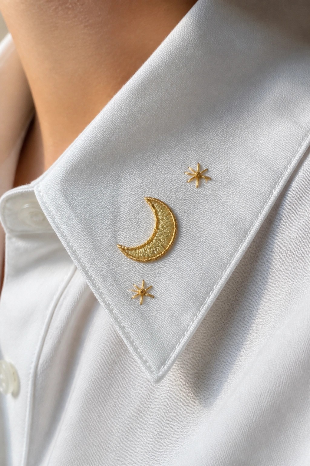 White collared shirt with gold embroidered crescent moon and stars.