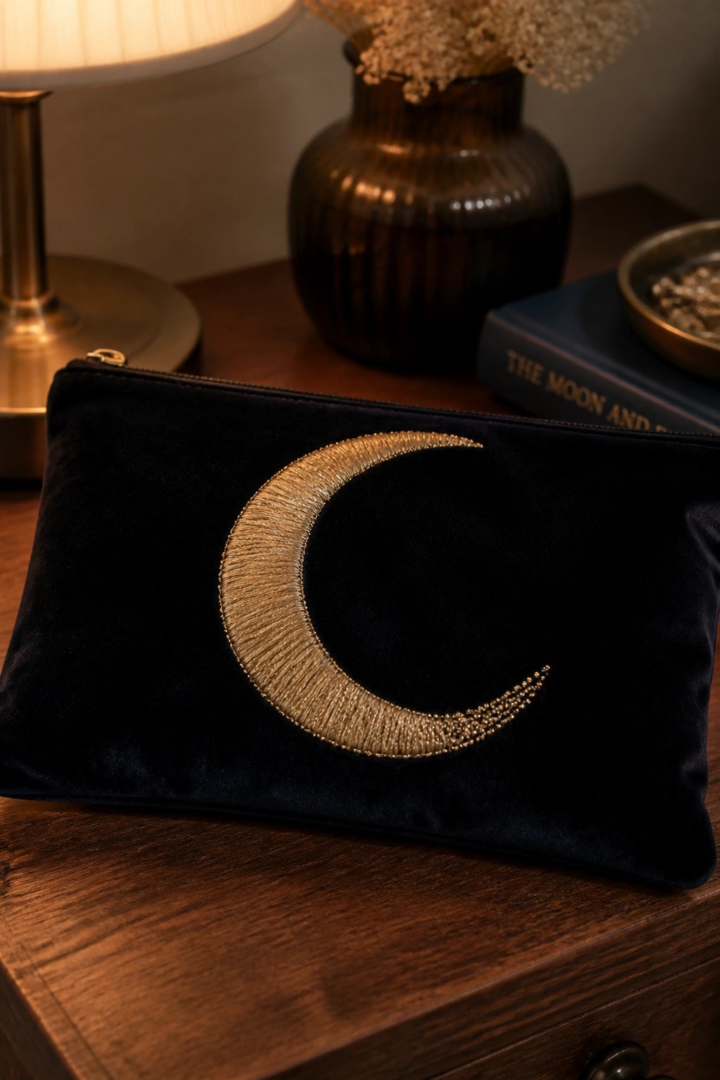 Navy velvet pouch with gold crescent moon embroidery on wooden table.